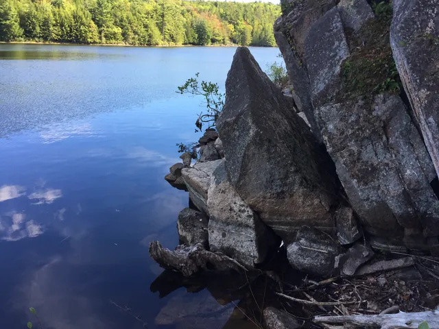 A pointed granite rock face rising out of the lake, with the stones at its foot