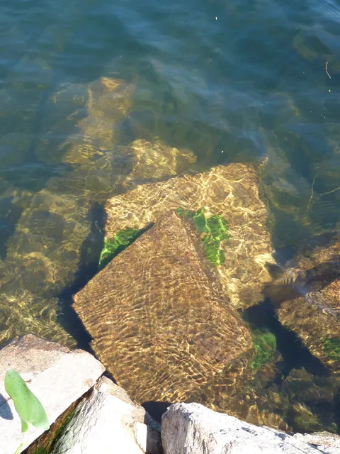 Looking down through clear water at a large squared stone block on the lake bottom