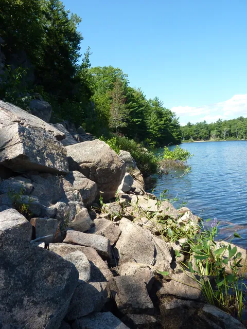 A jumble of granite blocks running down to blue water, with the lake and far shore beyond