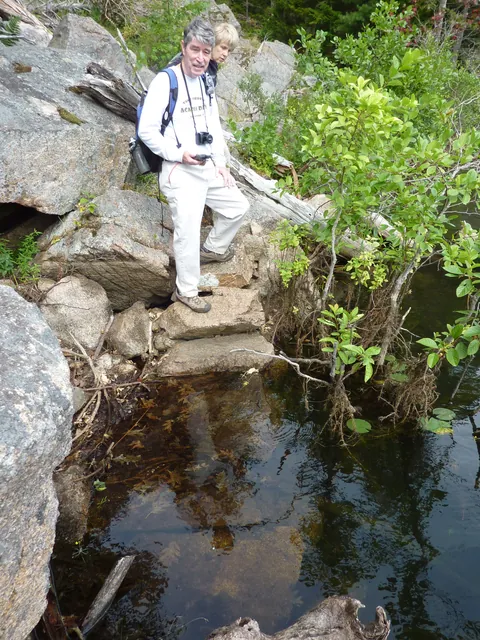 A hiker stands on squared stone steps that lead down into dark water