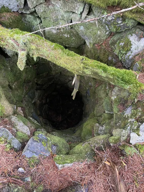 Looking down into a deep round well lined with stones