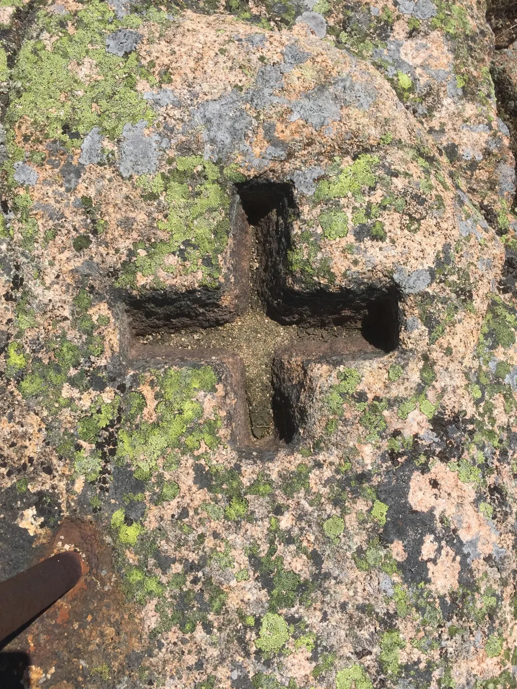 A cross chiseled deep into lichen-covered pink granite