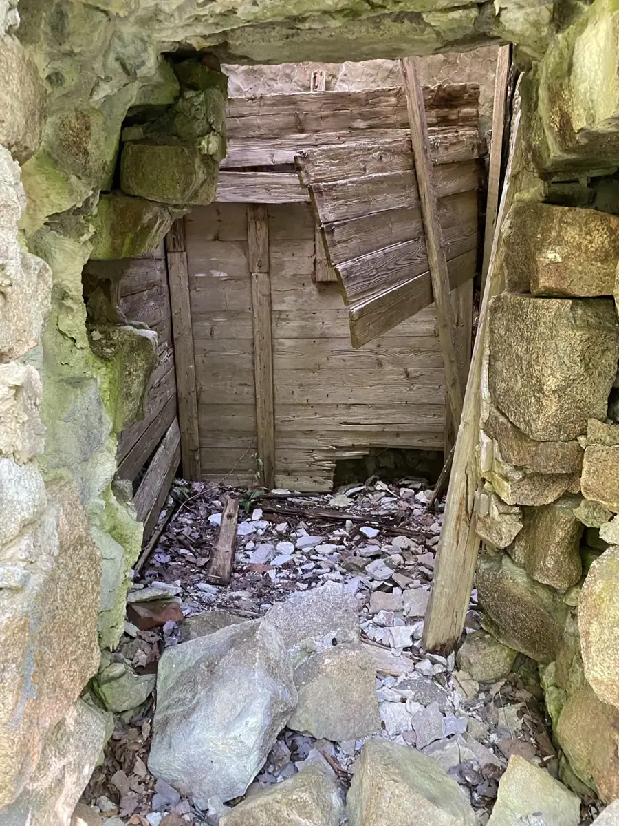 Inside the stone tower: granite walls around a broken wooden door and fallen rubble