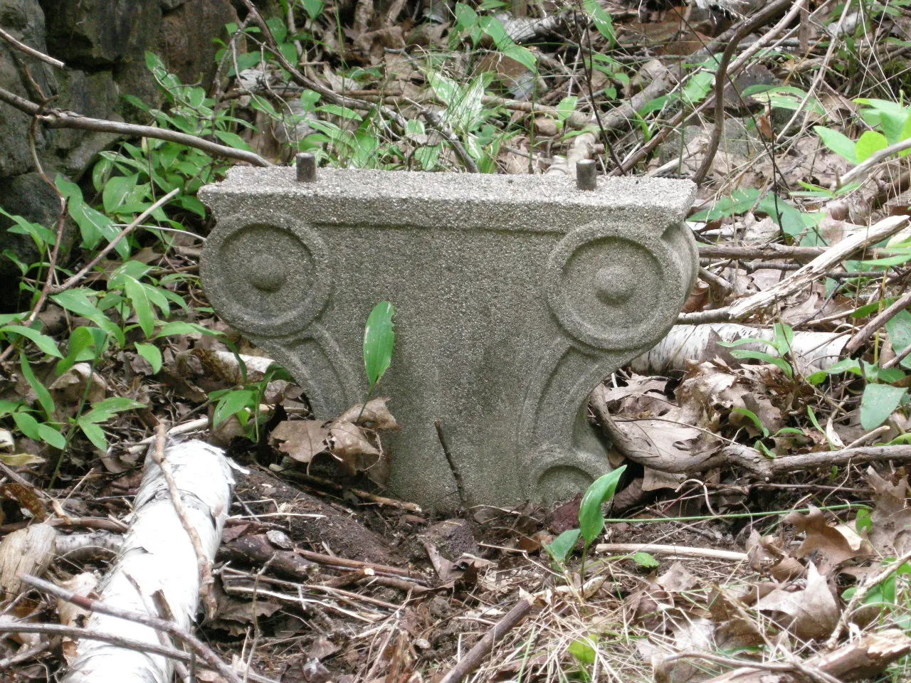 A carved stone capital with scroll ends lying in leaves