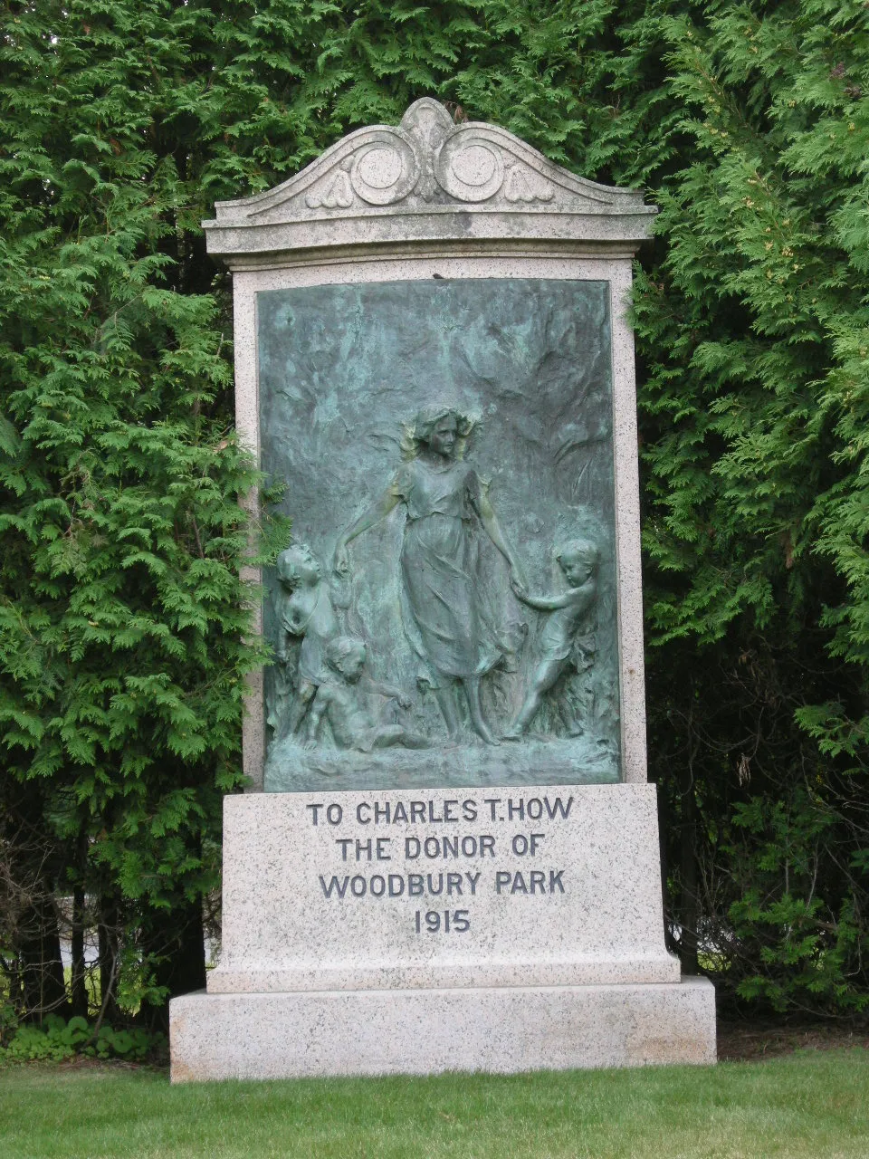 Granite memorial with a bronze relief of a woman leading children, inscribed To Charles T. How the donor of Woodbury Park 1915