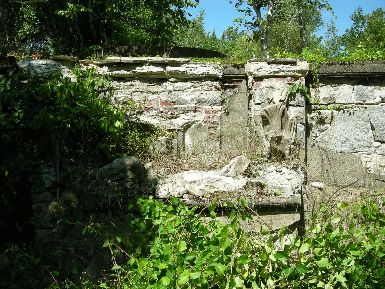 A ruined terrace wall of stucco and decorative concrete in summer woods