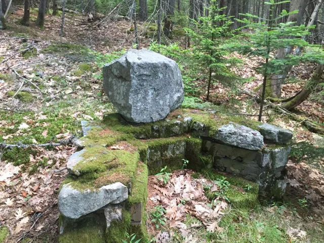 A fireplace with a large pale boulder set as its back wall