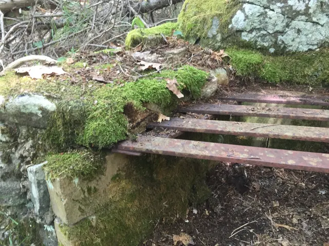 Close view of a rusted iron grate resting on granite blocks
