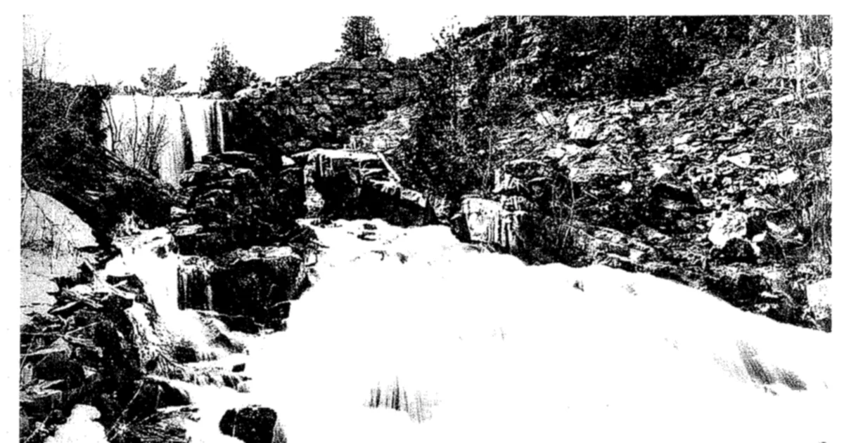 Water pouring over a broken stone dam among boulders