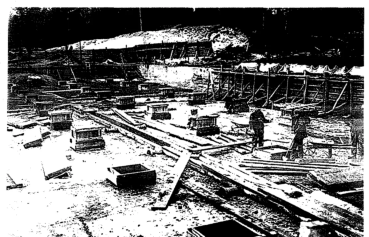 Workmen among concrete boxes and planks inside a filter bed